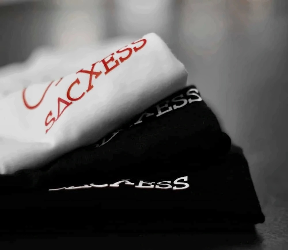 Folded SACXESS tees, white and black, with the printed SACXESS wordmark